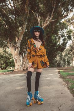 a woman in a hat and dress is riding roller skates