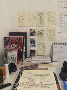 the desk is cluttered with drawings, pens, and notebooks on top of it