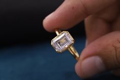 a close up of a person's hand holding a ring with a diamond in it