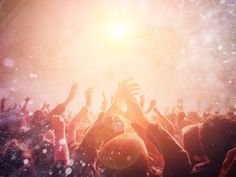 a group of people with their hands up in the air at a concert or festival