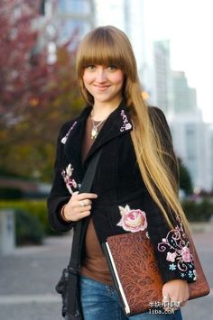 a woman with long blonde hair holding a purse