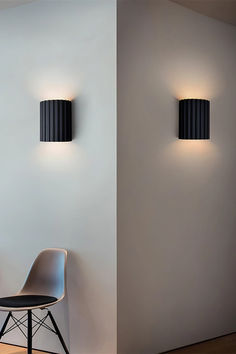 two lamps on the wall next to a chair