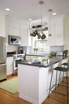 a kitchen with white cabinets, stainless steel appliances and an island in front of the stove