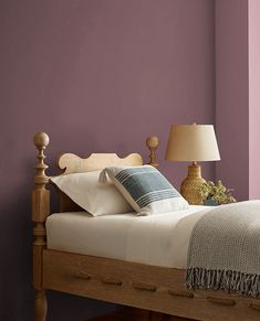 a bedroom with purple walls and white bedding in the center, along with two lamps on either side of the bed