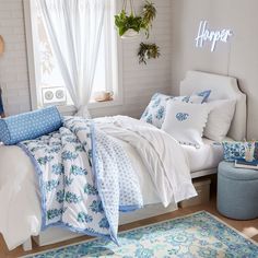 a bedroom with white and blue bedding, pillows and rugs on the floor