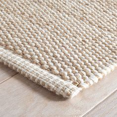 a beige rug on top of a wooden floor next to a wood flooring board