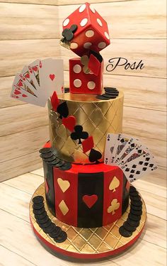 a three tiered cake decorated with playing cards and dice on the top, sitting on a wooden table