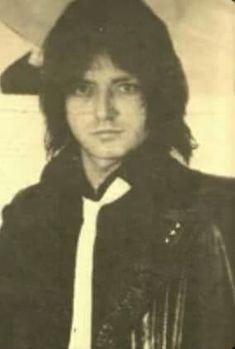 an old black and white photo of a man with long hair wearing a leather jacket