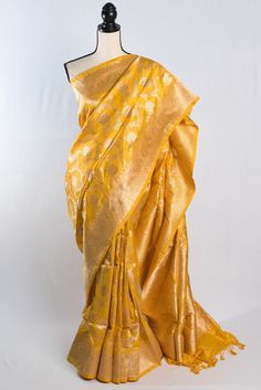 Step out in style with our Silk Mark Certified Jangla Banarasi Saree in Bright Yellow. This stunning saree features a traditional jangla pattern on luxurious silk fabric, making it a perfect blend of elegance and tradition. The bright yellow hue adds a pop of color to any ensemble and is sure to turn heads at any special occasion. The Silk Mark certification ensures the authenticity and quality of the silk, making it a timeless investment piece for your wardrobe. Whether you're attending a wedding or a festive celebration, this banarasi saree is a must-have for any lover of Indian ethnic wear. This is a SILK MARK CERTIFIED Saree. Color : Bright Yellow and Gold. Blouse Piece : Yes ( cut and separated from the saree ). Fall Pico : Yes.  Care: Dry-Clean Only. Traditional Yellow Banarasi Silk Saree, Bridal Banarasi Saree, Saree For Haldi, Yellow Handloom Banarasi Silk Dupatta, Luxury Yellow Banarasi Silk Saree, Semi-stitched Yellow Banarasi Silk Saree, Yellow Handloom Banarasi Silk Pre-draped Saree, Gold Saree, Gold Blouse