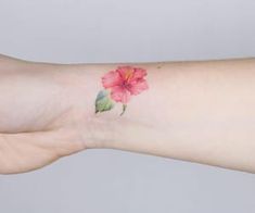 a woman's arm with a pink flower tattoo on the left side of her wrist