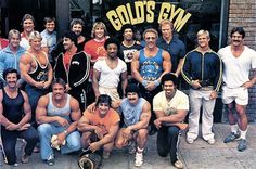 a group of men standing next to each other in front of a building with gold's gym on it