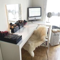 a white desk topped with a computer monitor and lots of makeup on top of it