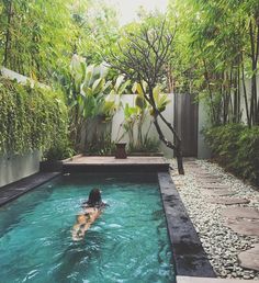 a person swimming in a pool surrounded by trees