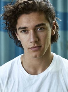 a black and white photo of a man with curly hair wearing a t - shirt