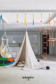 there is a teepee tent in the middle of this room with toys hanging from it