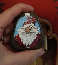 a hand holding a painted rock with a santa clause on it