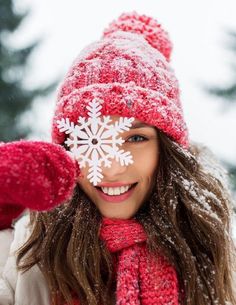 a woman wearing a red hat and scarf with snow flakes on her face