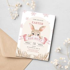 an easter egg hunt party with bunny ears and pink ribbon on the front, next to some flowers