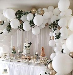 a table with white balloons, cake and desserts on it in front of a backdrop