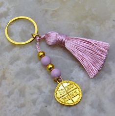 a pink tasseled keychain with a gold medallion and beads on it