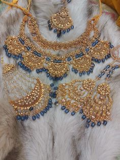 an elaborate necklace and earring set is displayed on a fur covered surface with other jewelry items