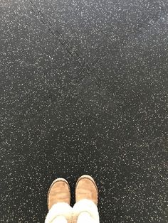 someone is standing in front of a black floor with white speckles on it