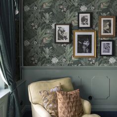 a living room with green wallpaper and pictures on the wall, along with a chair