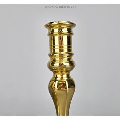 a gold colored metal candle holder on a white background with the words indigobird trade written below it