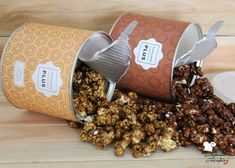 two tins filled with popcorn sitting on top of a wooden table