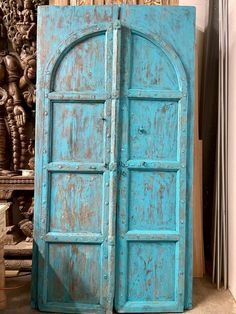 an old blue door sitting next to a pile of wood planks in a room