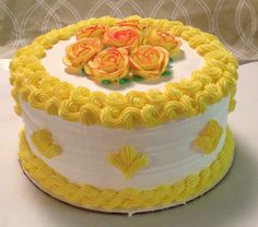 a yellow and white cake with roses on top