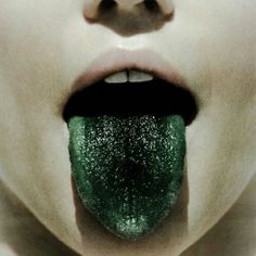 a woman's mouth with green glitter on it and her tongue sticking out to the side