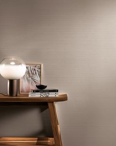 a lamp sitting on top of a wooden table next to a book and a painting