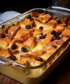 a casserole dish with bread and raisins in it on a wooden table