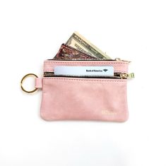 a pink wallet with money sticking out of it's front pocket and a gold keychain