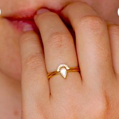 a close up of a person's hand with a gold ring on her finger