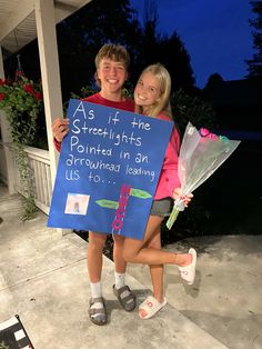 a boy and girl holding a sign that says as if the street lights are pointed in an arrow