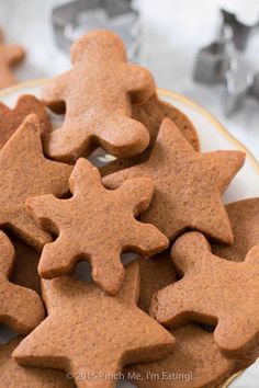 some cookies that are on a plate with cookie cutters in the background and one is cut out to look like stars