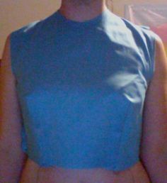 a woman wearing a blue top standing in front of a mirror with her hands on her hips