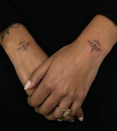 two people holding hands with small tattoos on them