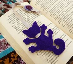 an open book with a purple felt animal on it