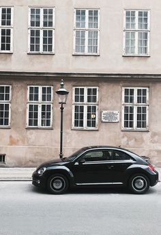 a black car is parked on the side of the road in front of a building