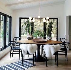 a dining room table with chairs and potted plants