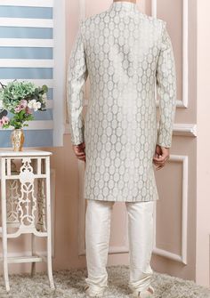 Ready-Made Sherwani With Trouser. Jacquard Brocade Fabric Top. Art Dupion Churidar Ready Made Trouser. Crafted in Chinese Collar Neck, and Full Sleeve. Satin Lining with Plain Work. High-Quality Matching Buttons. Please Note: The footwear shown in the picture is for presentation and photography purpose only. Color: There might be slight color variation due to lightings and flashes while photo shooting. The color may also vary because of different screen resolutions. Wash Care: Dry Clean Only. Traditional Party Wear, Indo Western Sherwani, Chinese Collar, Readymade Saree, Dupion Silk, Collar Neck, Silk Trousers, Top Art, Indo Western