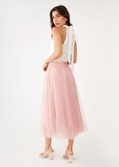 The Sue Skirt in romantic blush tulle takes playful elegance to the next level! This dreamy tulle midi skirt features an elastic waistband and satin tie in the most feminine color. Channel your inner Carrie Bradshaw and style this piece with a simple top, your most fun heels, and a fabulous bag while exploring the streets of your favorite city! High rise Satin-covered elastic waistband Ribbon bow tie front Midi length Fully lined The lining is approx. 3 inches shorter than tulle Fabric: Tulle, 1 Elegant Midi Tulle Skirt, Elegant Tulle Midi Skirt, Chic Tulle Lined Maxi Skirt, Chic Pink Wedding Skirt, Chic Voluminous Tulle Maxi Skirt, Pink Summer Wedding Bottoms, Spring Flowy Tulle Bottoms, Pink Tulle Full Skirt Bottoms, Pink Tulle Full Skirt