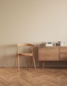 a wooden chair sitting next to a dresser on top of a hard wood floor in an empty room