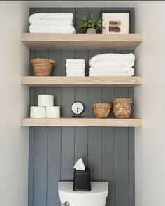 the shelves above the toilet are filled with towels and other bathroom items, including folded towels