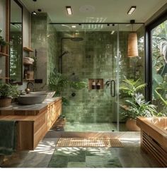 a green tiled bathroom with two sinks and a walk in shower next to a large window