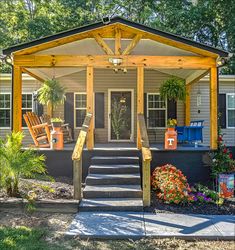 a porch with steps leading up to the front door and covered in wood planks