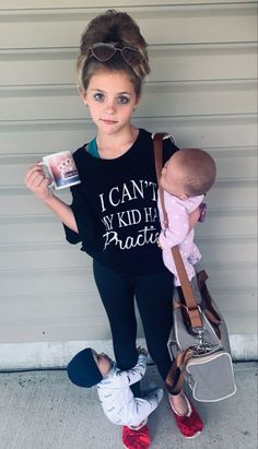 a woman holding a baby in her arms while standing next to a garage door with the words i can't my kid has plastic on it